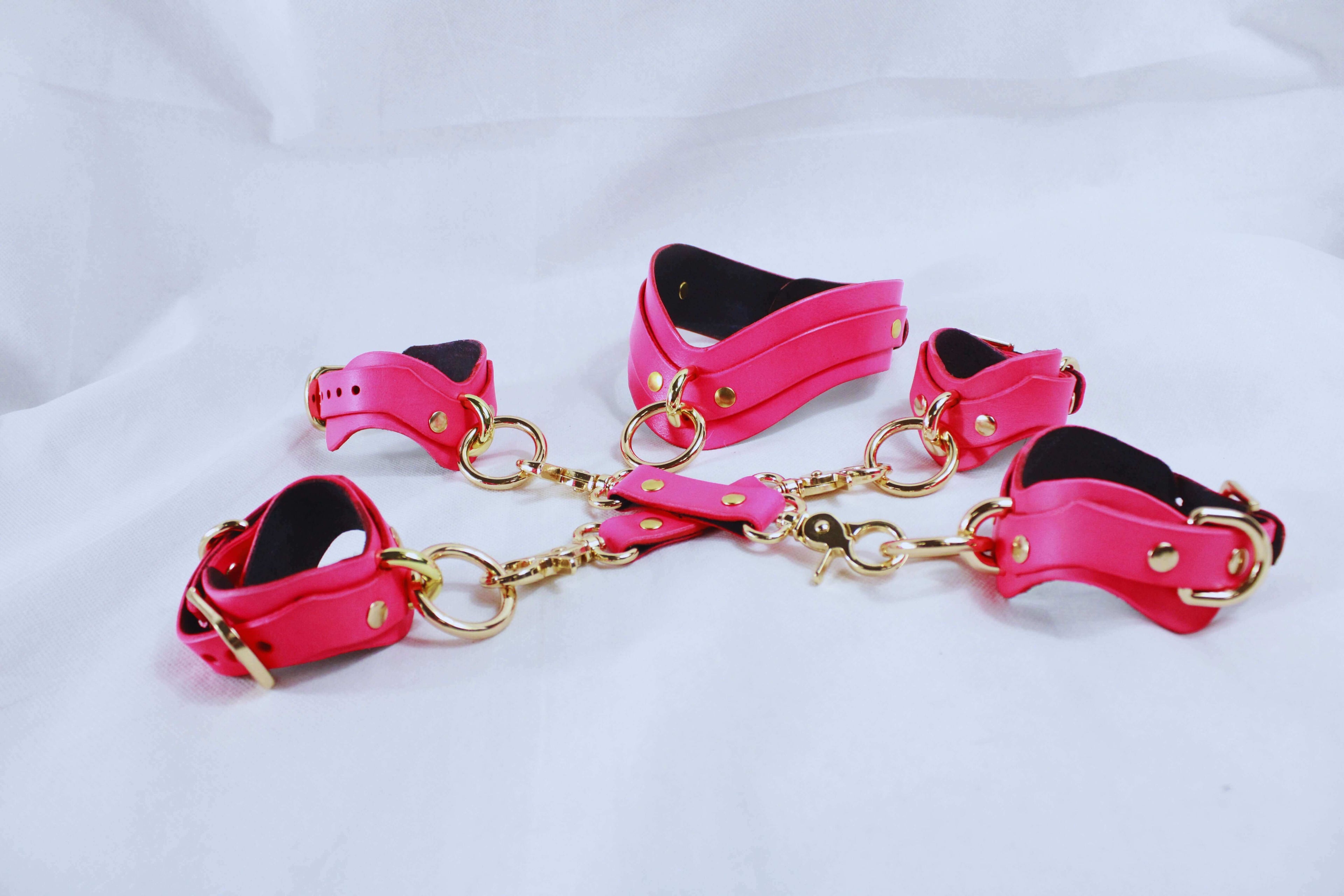 Set of pink bondage cuffs connected by gold chains, designed for enhancing BDSM intimacy.