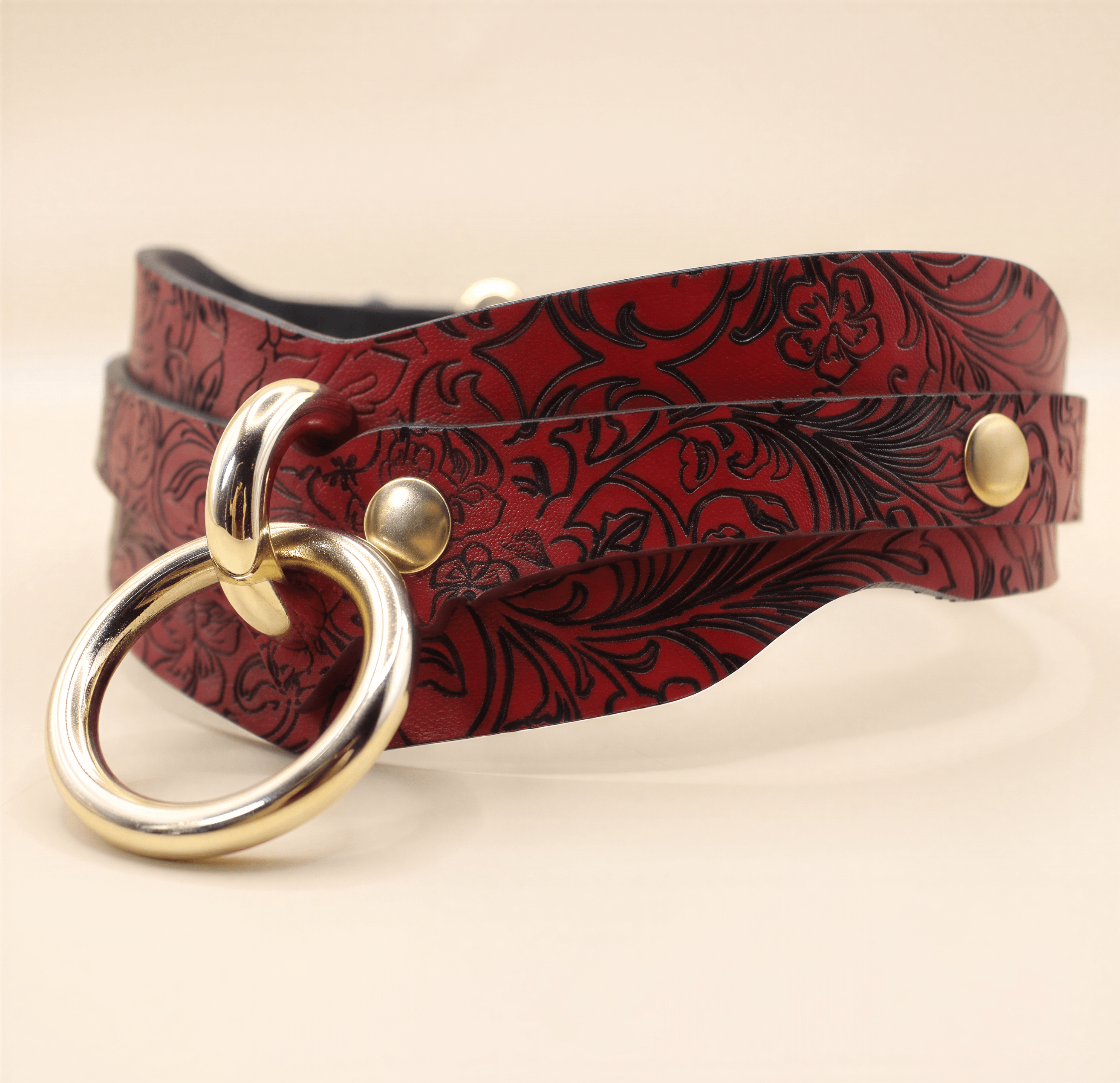 A red leather choker necklace with a floral pattern and a gold-colored metal ring.