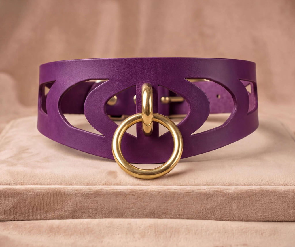 A purple leather choker necklace with a gold ring and a cutout design on the front.