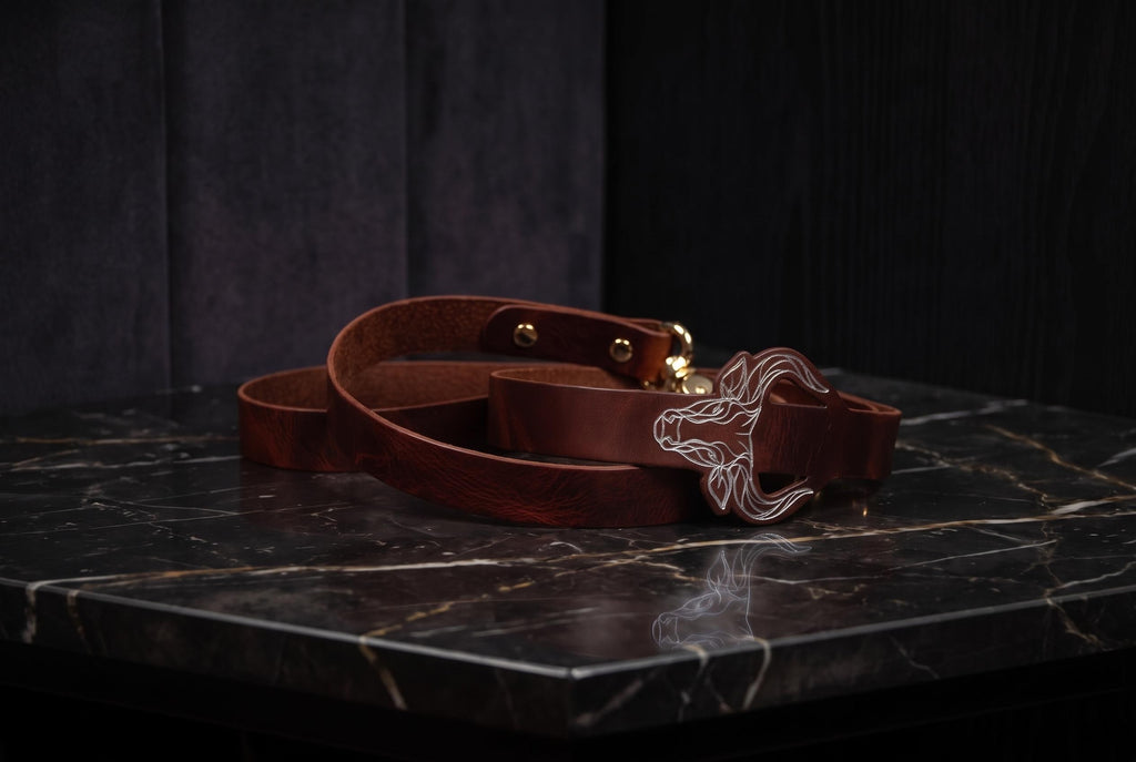 A brown leather belt with a metal buckle is placed on a black marble surface.