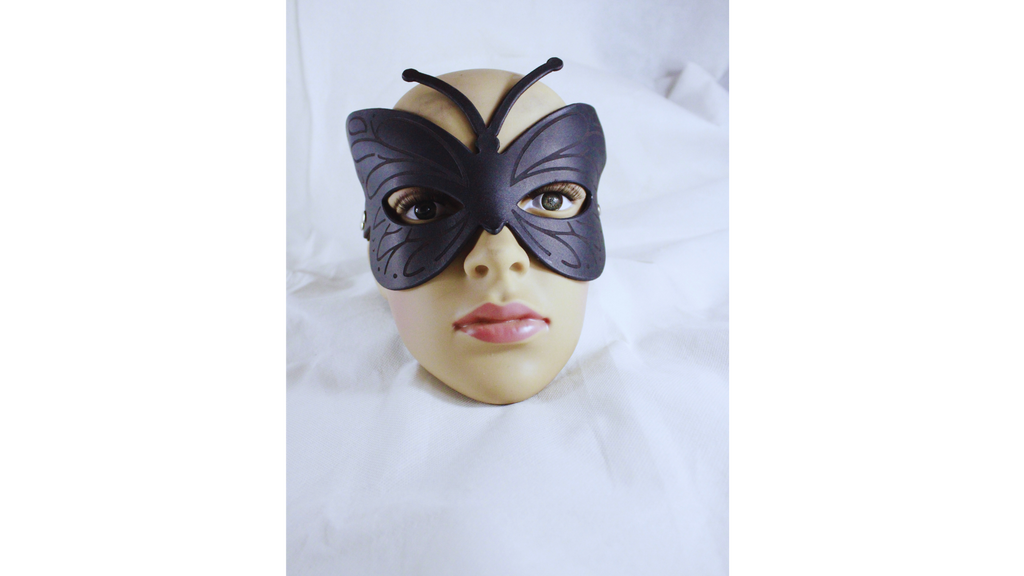 A mannequin head wearing a black butterfly-shaped mask with large eyes and a small nose.