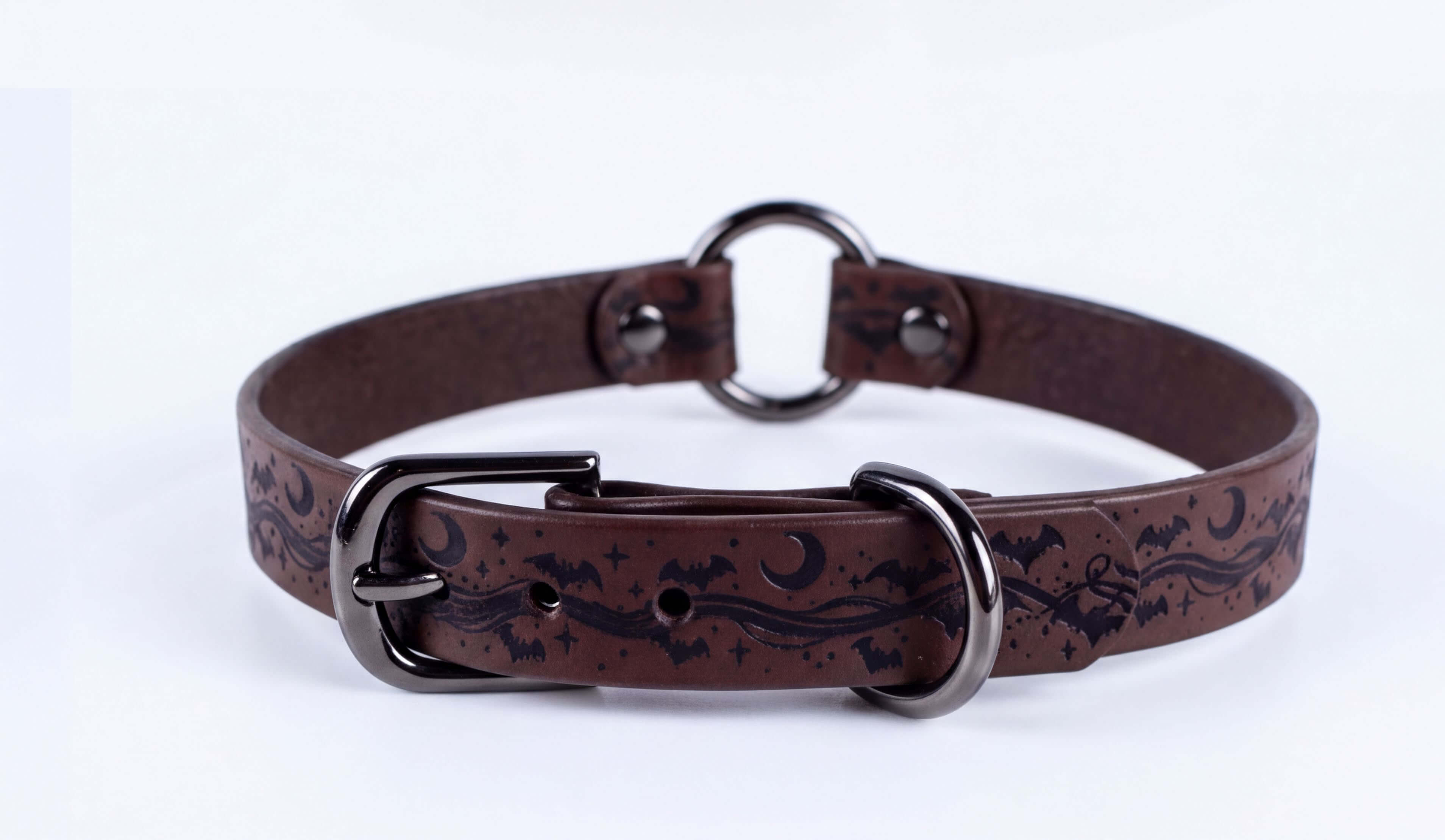 A brown leather collar with a metal buckle and a decorative pattern of bats and stars.