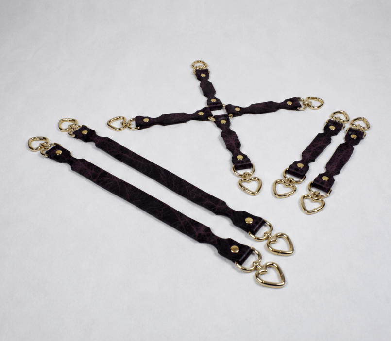 a collection of purple leather straps with gold-colored heart-shaped buckles, arranged on a white background.