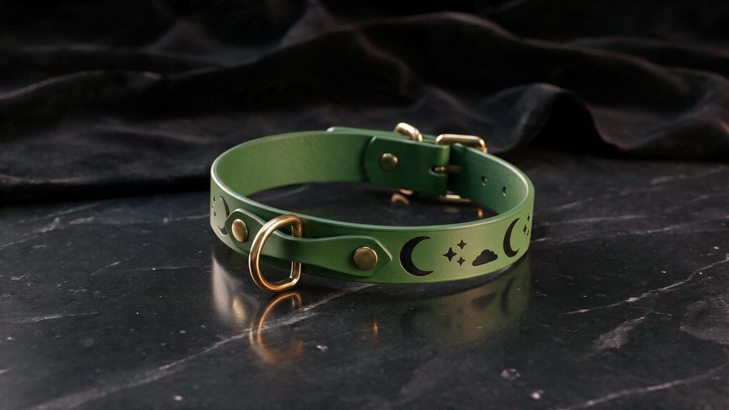 A green leather collar with a moon and star design on it, placed on a black marble surface.
