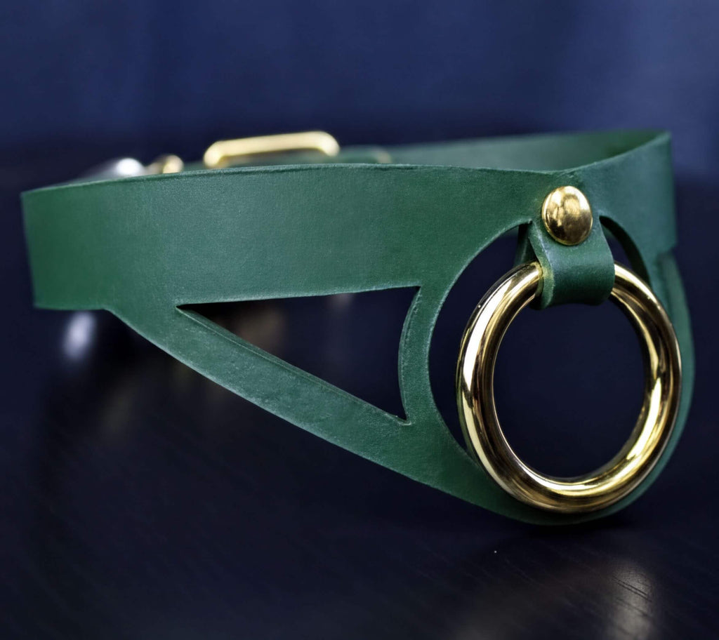 A close-up view of a green leather choker necklace with a gold-colored metal ring on the front.