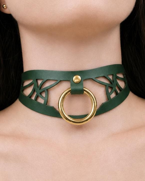 A close-up of a woman's neck wearing a green leather choker necklace with a gold ring.
