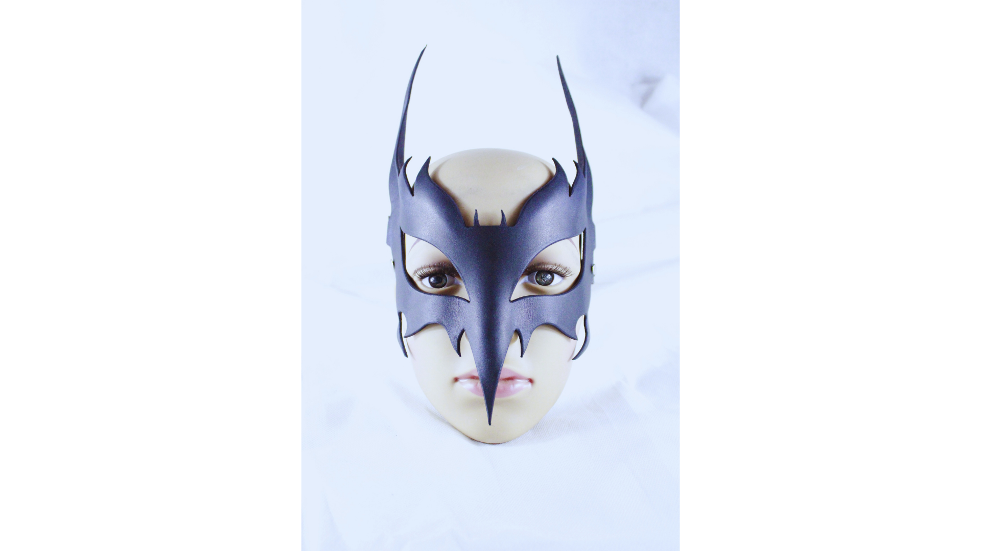 A mannequin head wearing a black mask with sharp teeth and a pointed nose, resembling a mask or costume.