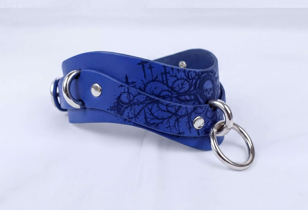 A blue leather choker necklace with a skull design on the front.