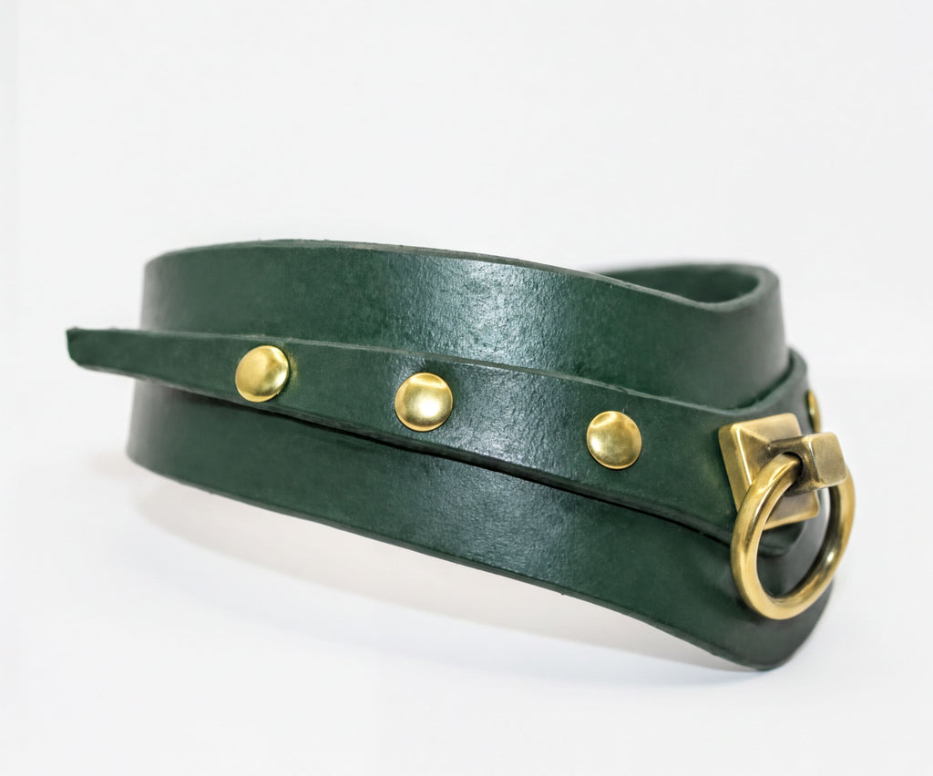 A green leather choker necklace with a brass buckle and three gold-colored studs.