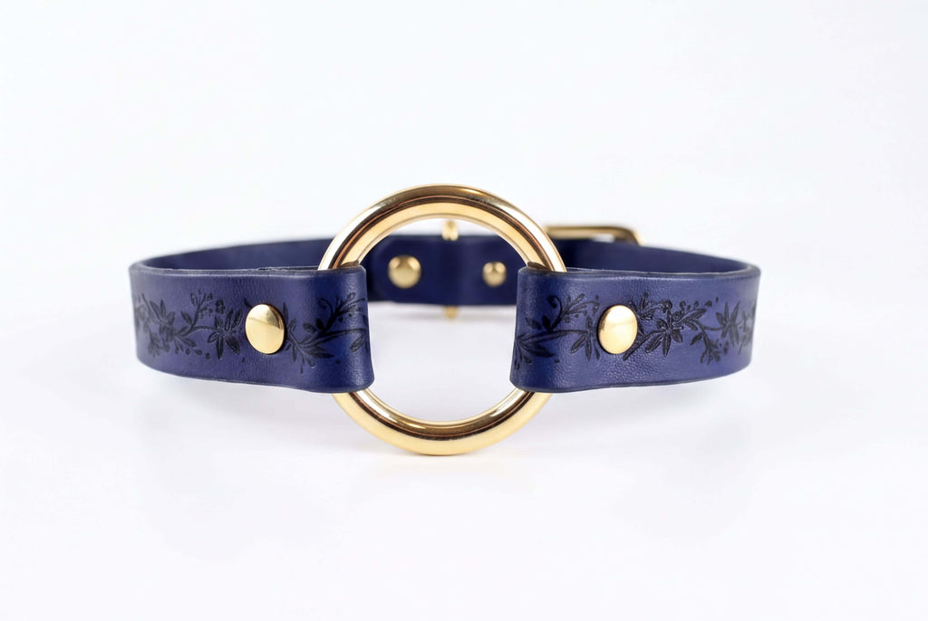 A blue leather choker necklace with a gold-colored circular buckle.