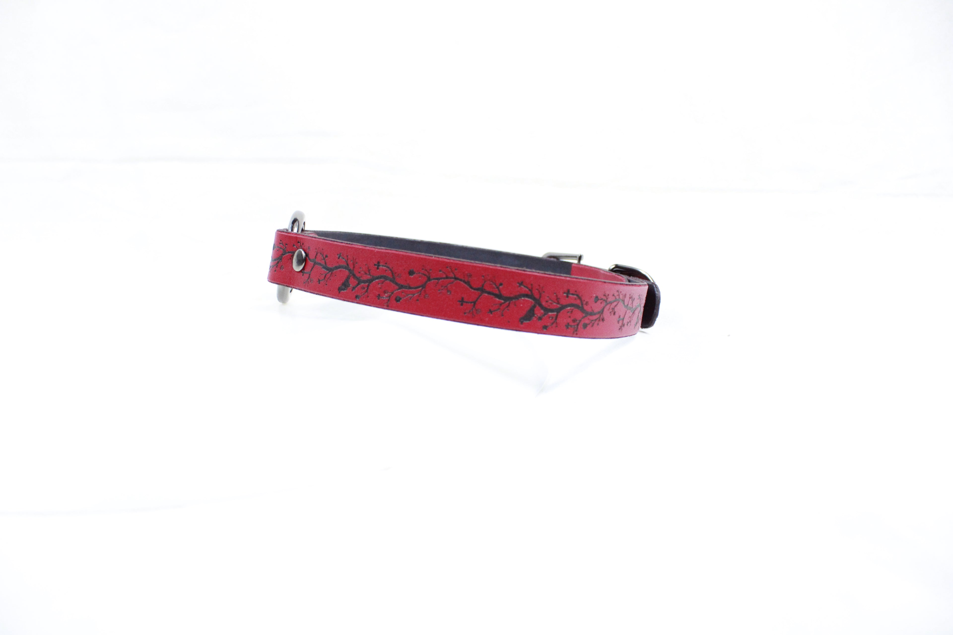A red dog collar with a black tree branch design.
