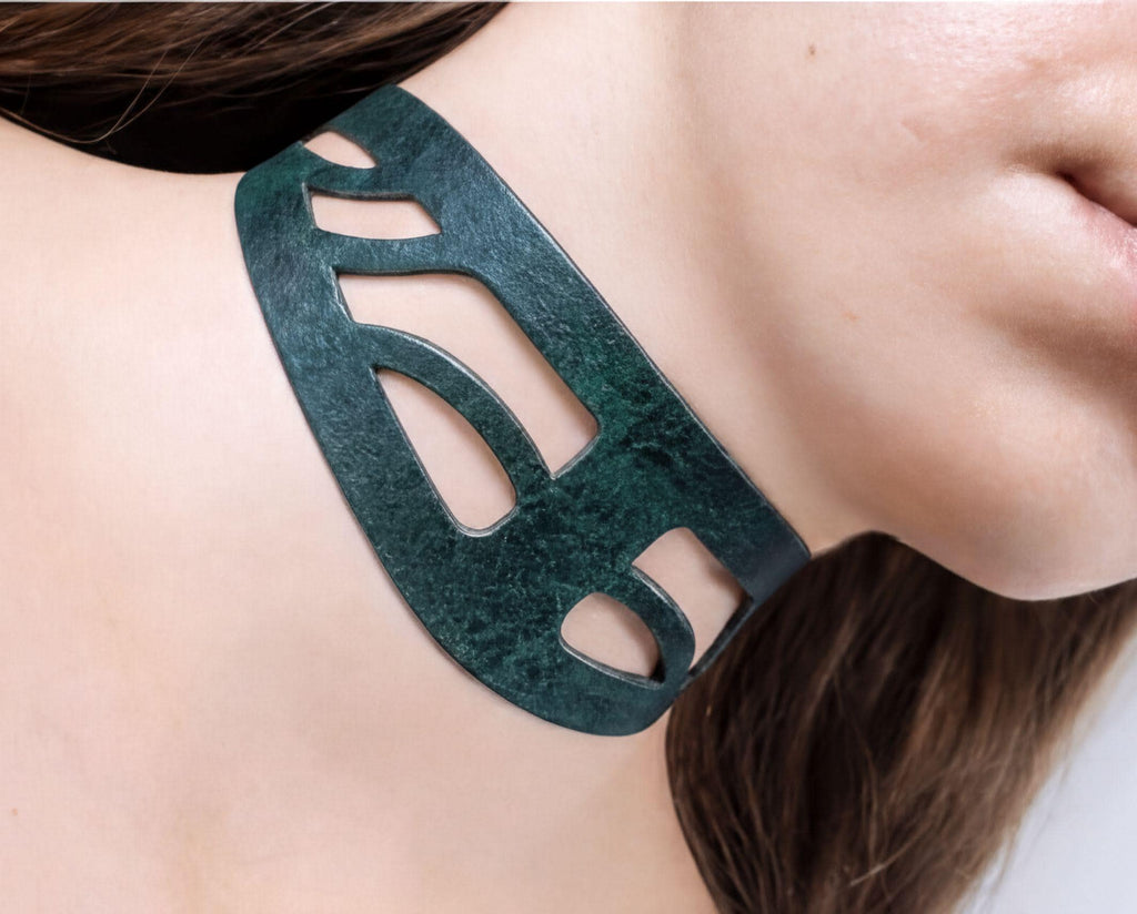 A close-up of a woman's neck wearing a green choker necklace with a unique cutout design.