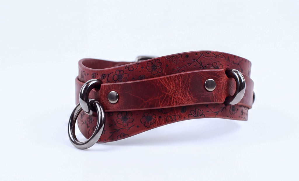 A red leather choker necklace with metal rings and a metal clasp.