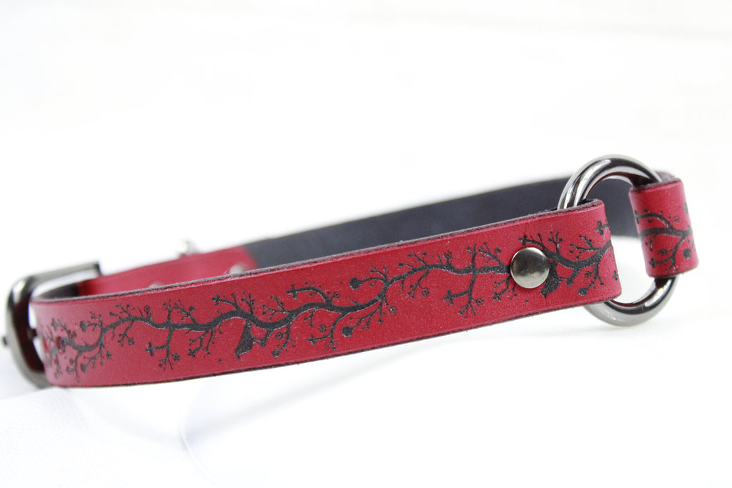 A red leather dog collar with a black tree branch design.