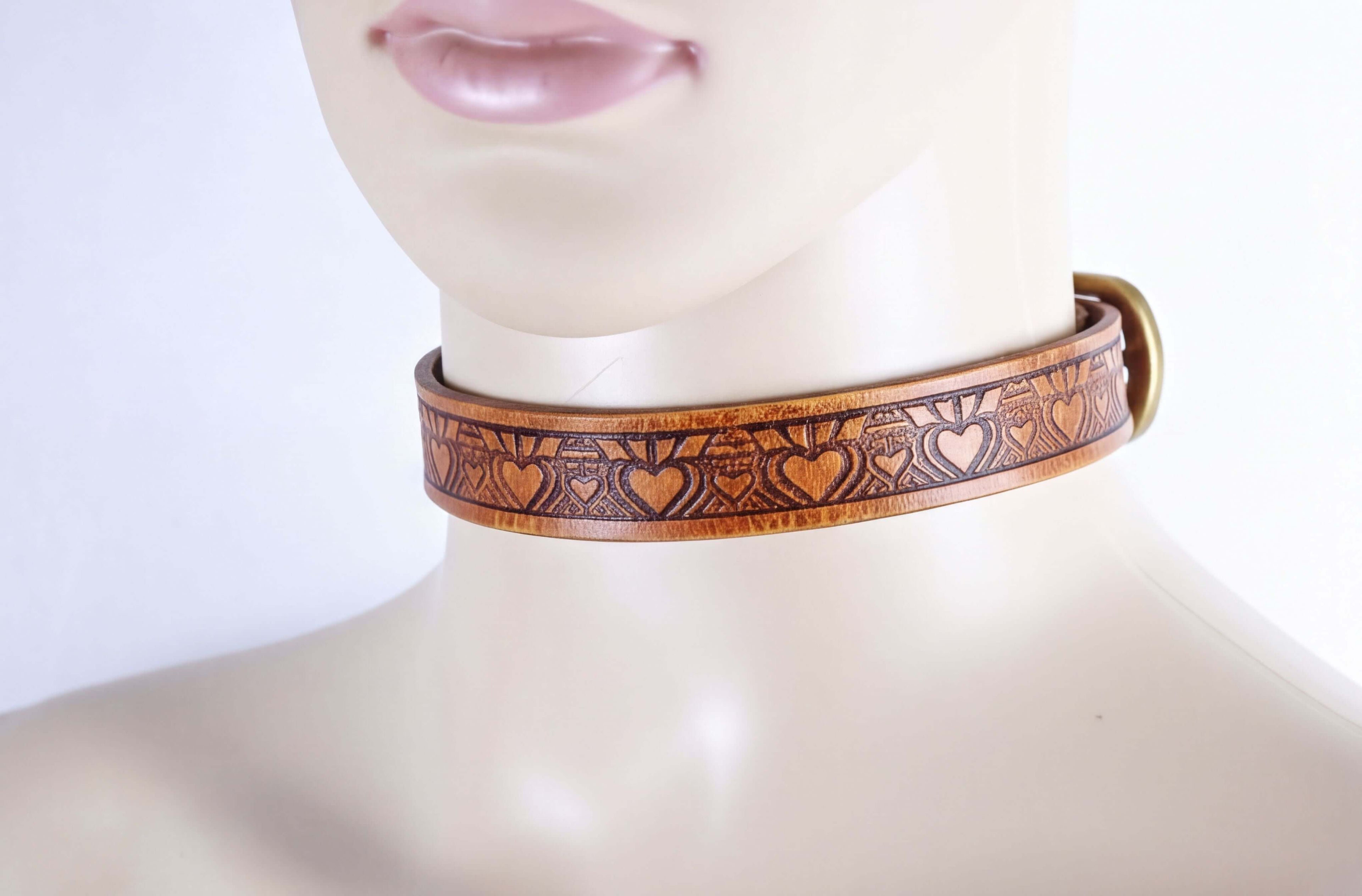 A close-up of a mannequin head wearing a brown leather choker necklace with a heart-shaped pattern.