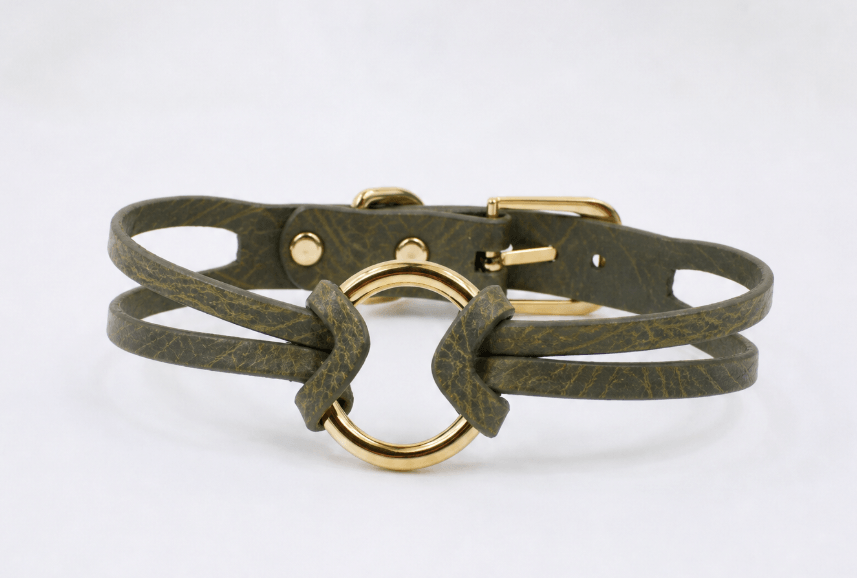 A dark green leather choker necklace with a gold-colored metal ring in the center.
