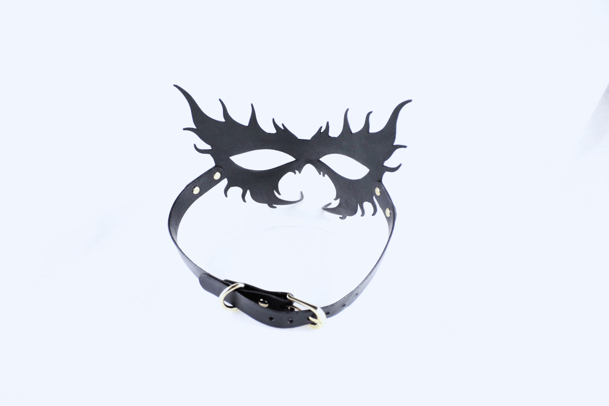 A black mask with a decorative design and a black leather strap.