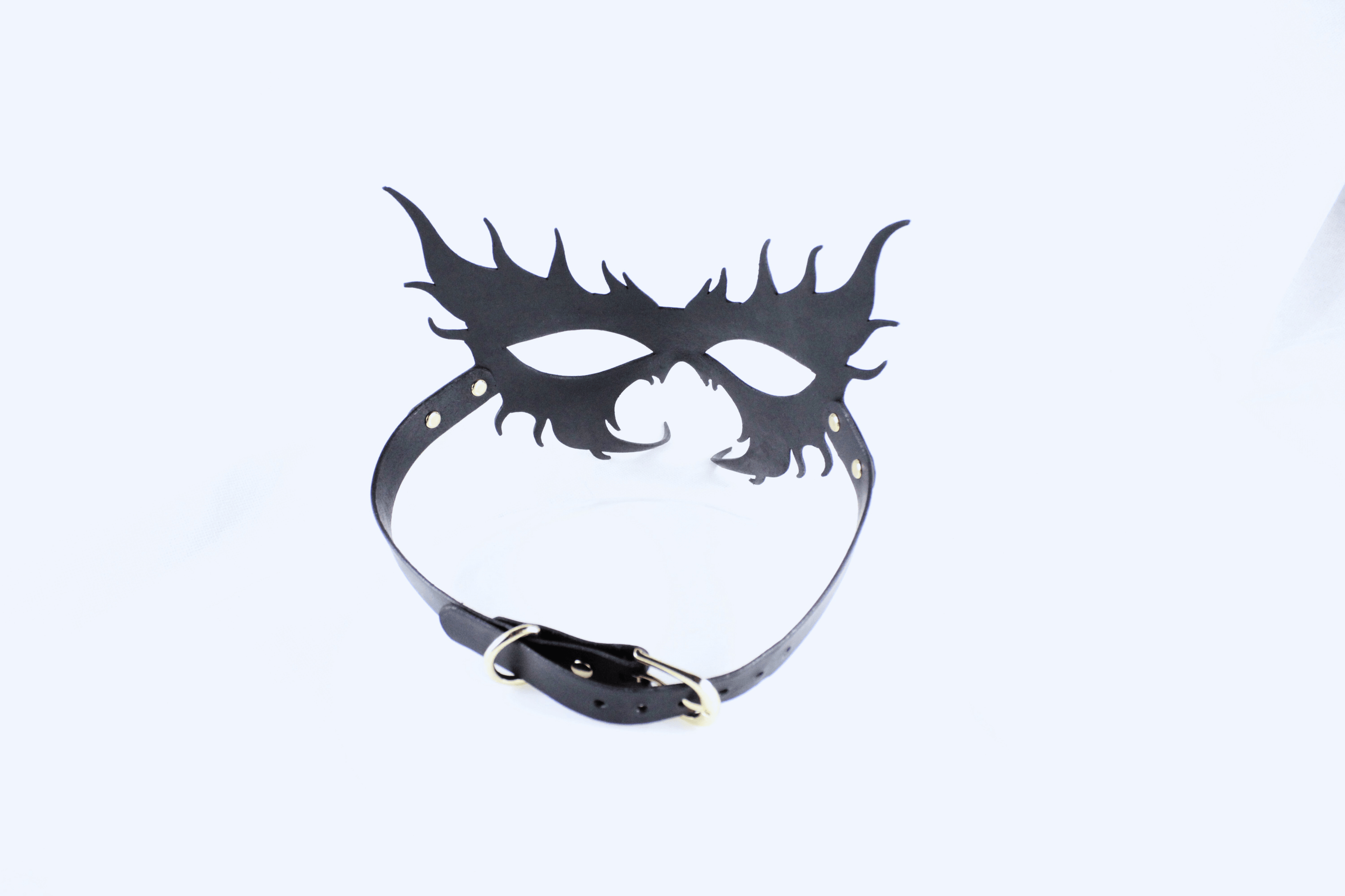 A black mask with a decorative design and a black leather strap.