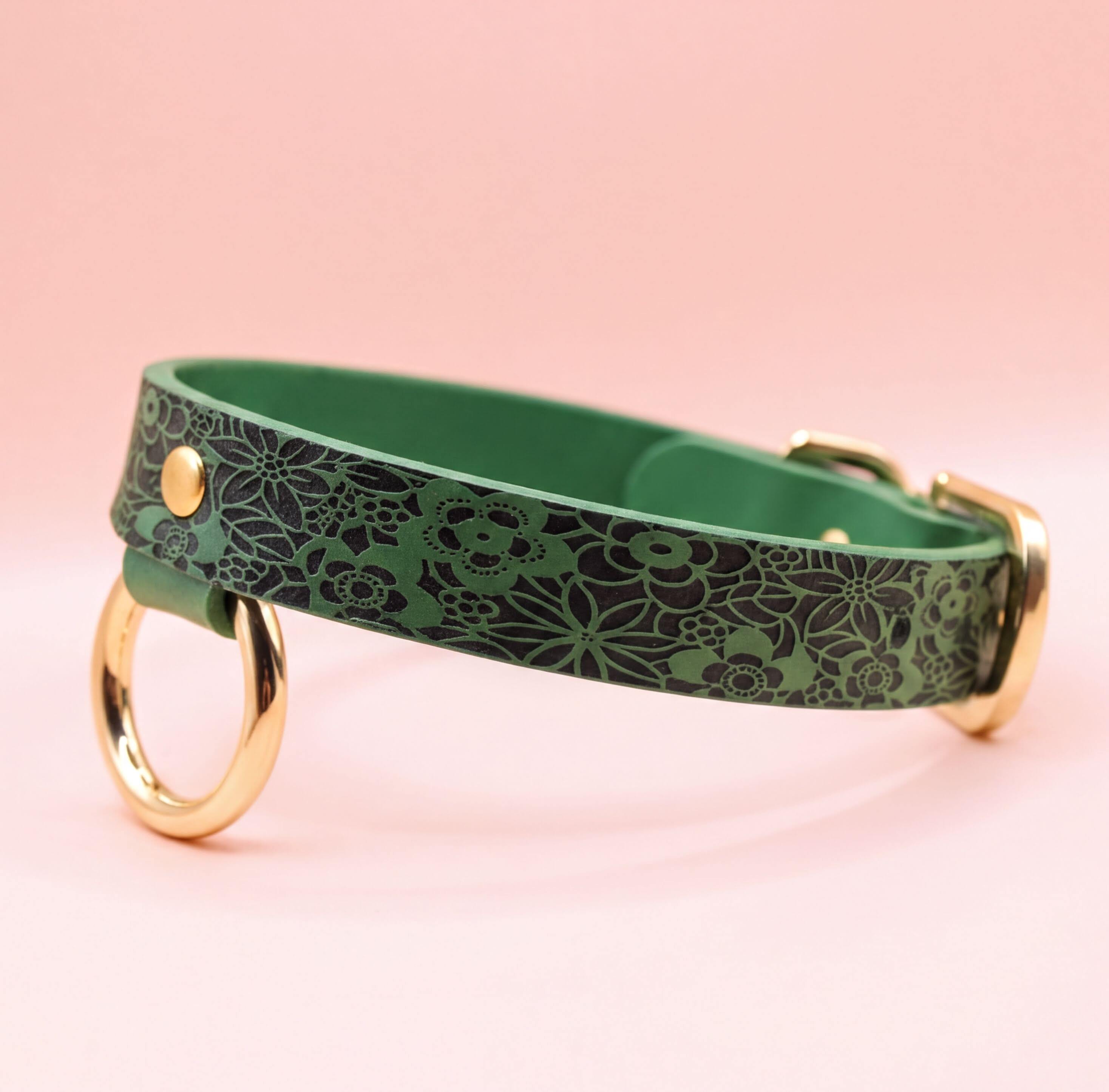 A green collar with a floral pattern and two gold rings on the sides.
