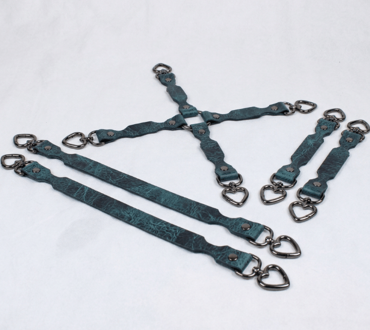A group of dark green leather straps with metal hardware, including heart-shaped buckles, arranged in a pattern on a white background.