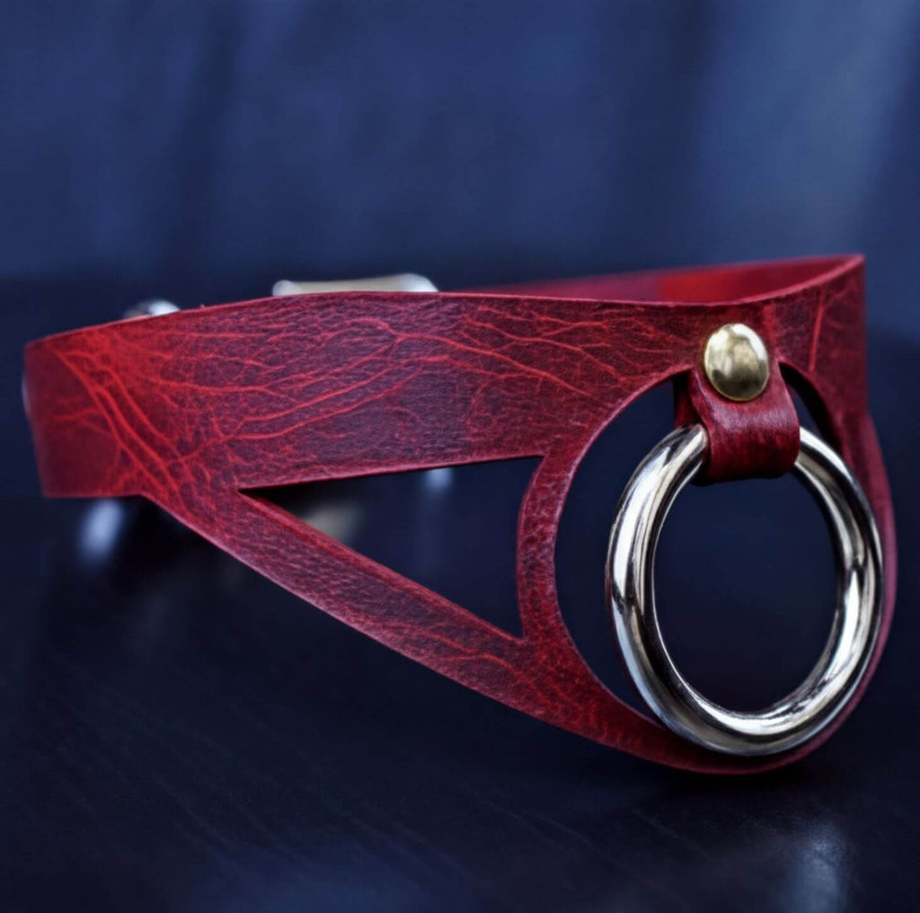 A red leather choker necklace with a metal ring and a gold-colored buckle.
