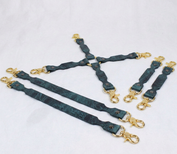 A group of dark green leather straps with gold metal clasps and buckles, arranged in a diamond-like pattern on a white background.