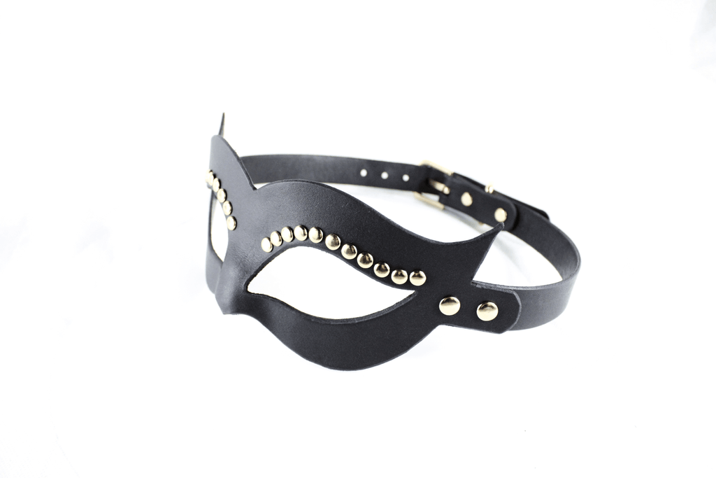 A black leather mask with gold studs on the sides and a black strap.