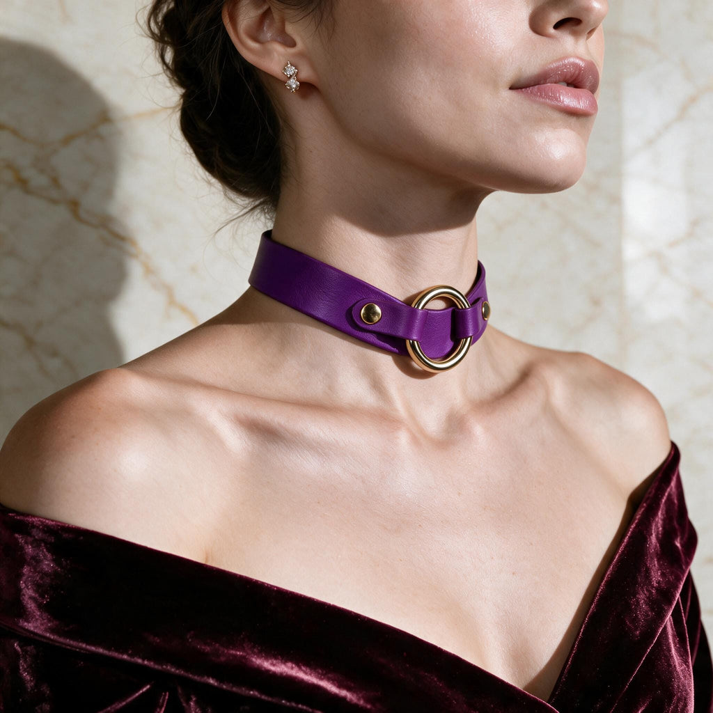 A woman wearing a purple choker necklace with a gold ring, posing against a marble background.