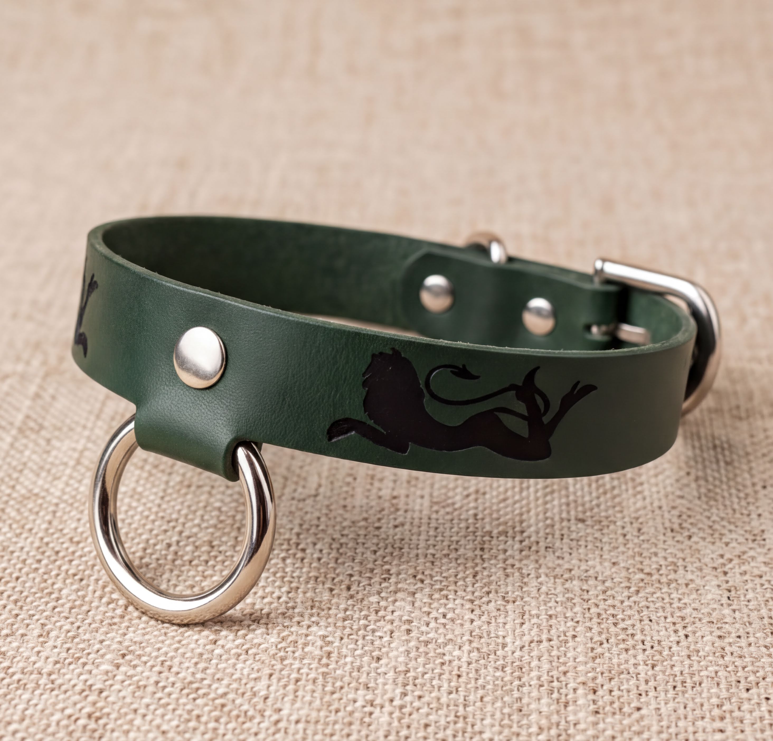 A green leather dog collar with a silver metal ring and a black lion silhouette design.