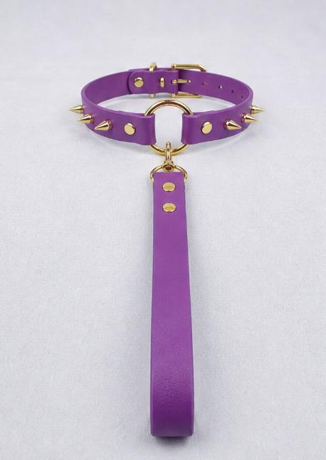 A purple spiked collar with gold studs and a gold-colored handle attached to it.