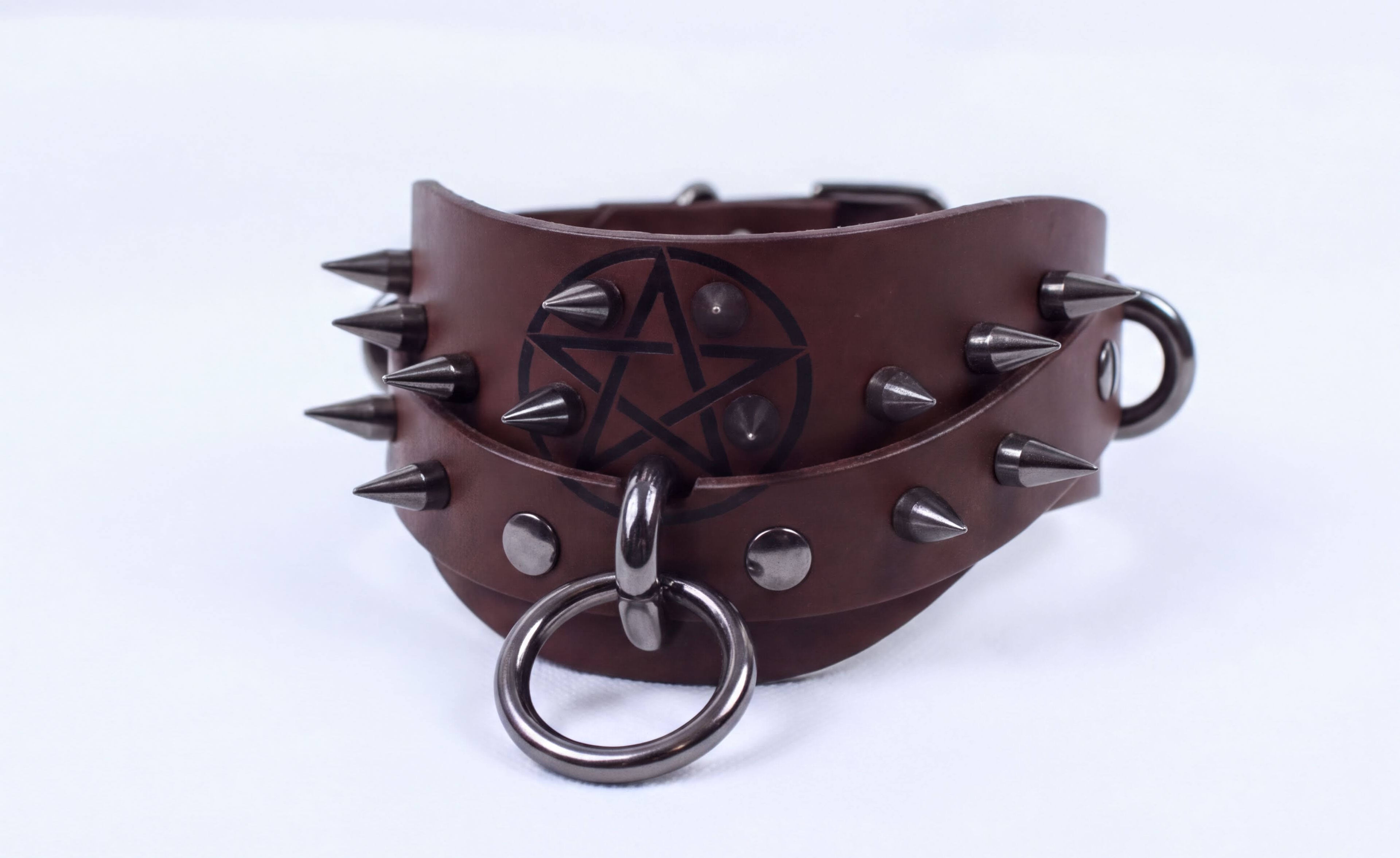 A brown leather bracelet with spikes and a pentagram symbol on it.