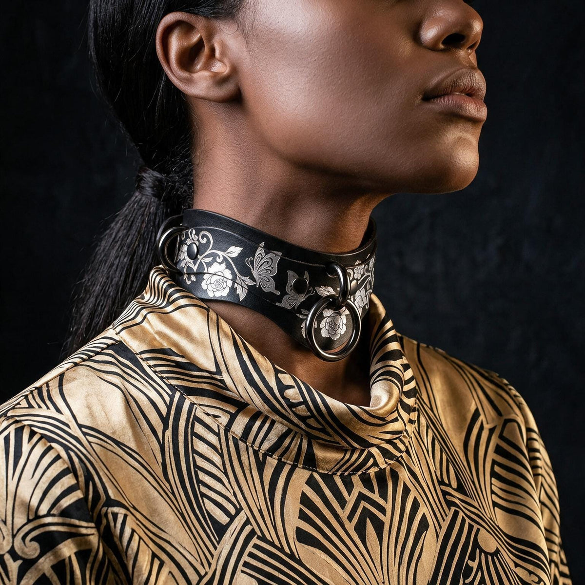 A close-up of a woman's neck and chest area, featuring a choker-style collar with a floral pattern and metal rings.
