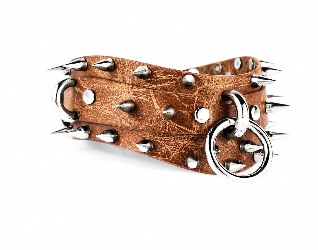 A leather belt with spikes protruding from it, and a metal ring attached to the belt.