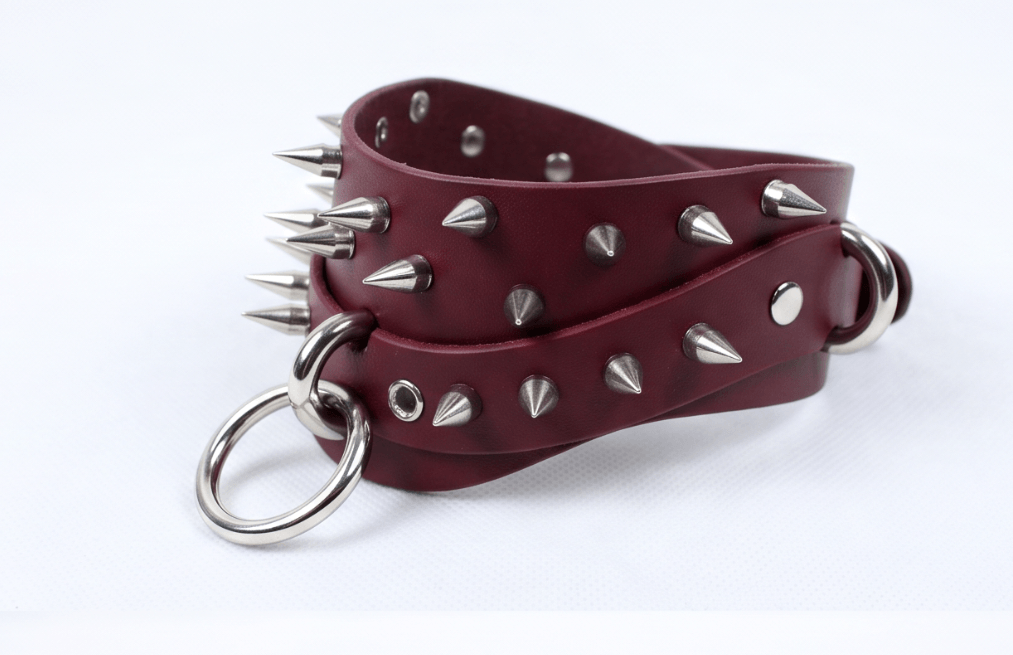 A burgundy leather choker necklace with silver spikes protruding from it.