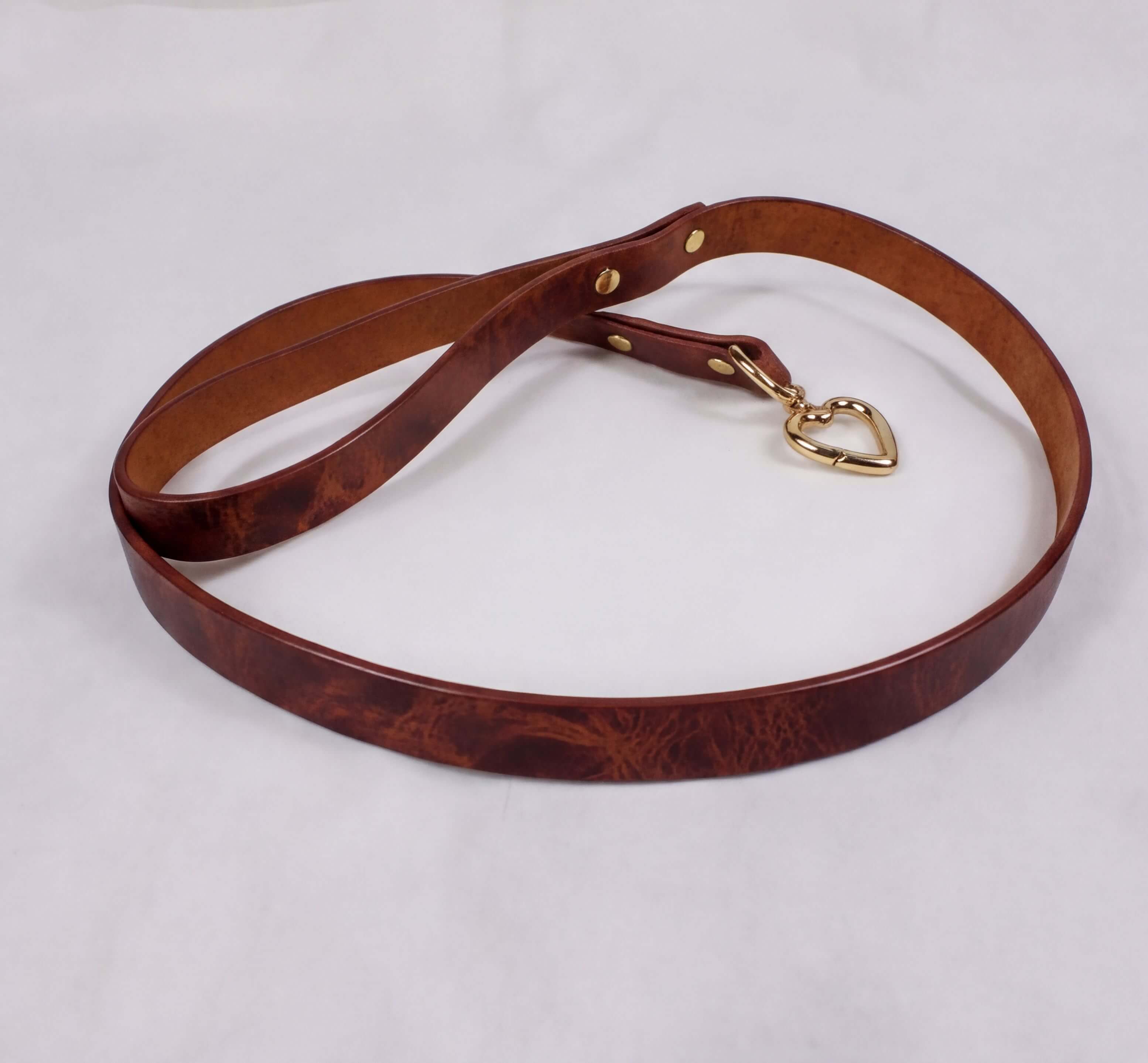 A brown leather dog collar with a heart-shaped charm attached.