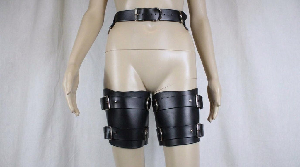 A mannequin wearing black leather knee pads with buckles.