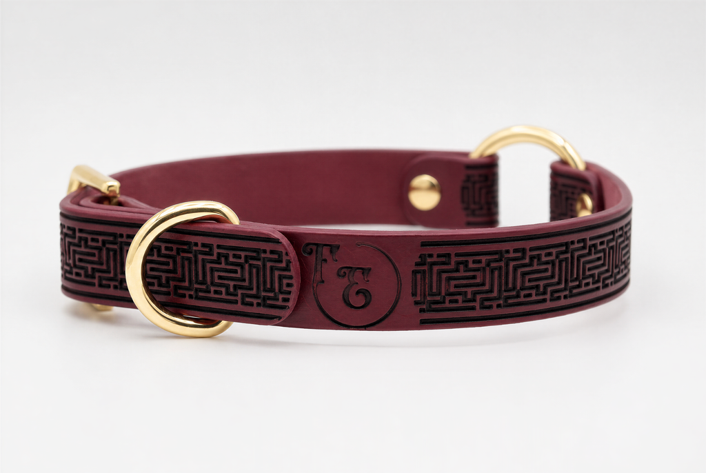 A burgundy leather dog collar with a black maze pattern and two gold-colored buckles.