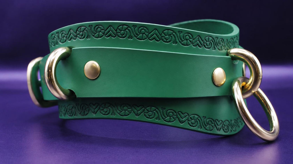 A green leather strap with embossed designs and two gold-colored metal rings on the ends, resting on a purple background.