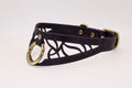 A purple leather choker necklace with a gold-colored metal ring and a cutout design on the front.