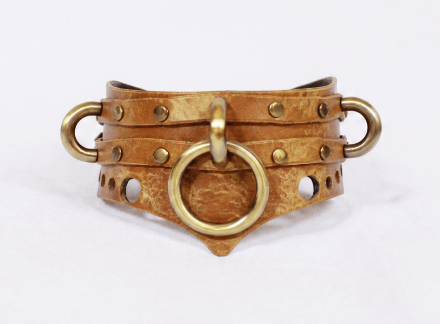 A brown leather corset with metal studs and a circular metal ring.
