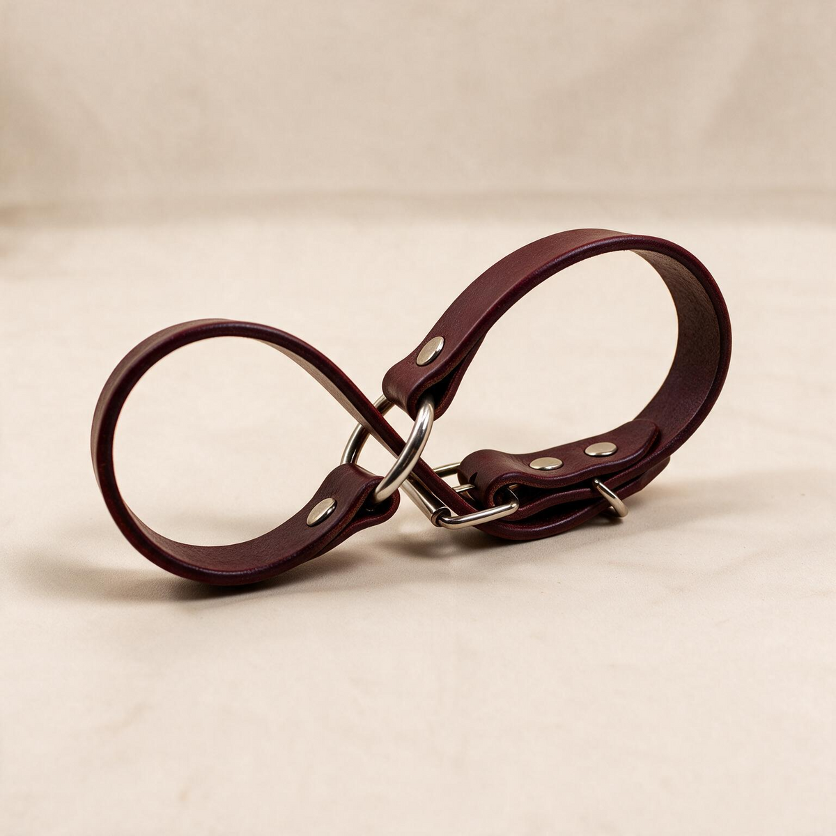 A burgundy leather strap with metal buckles and clips is shown in the image.