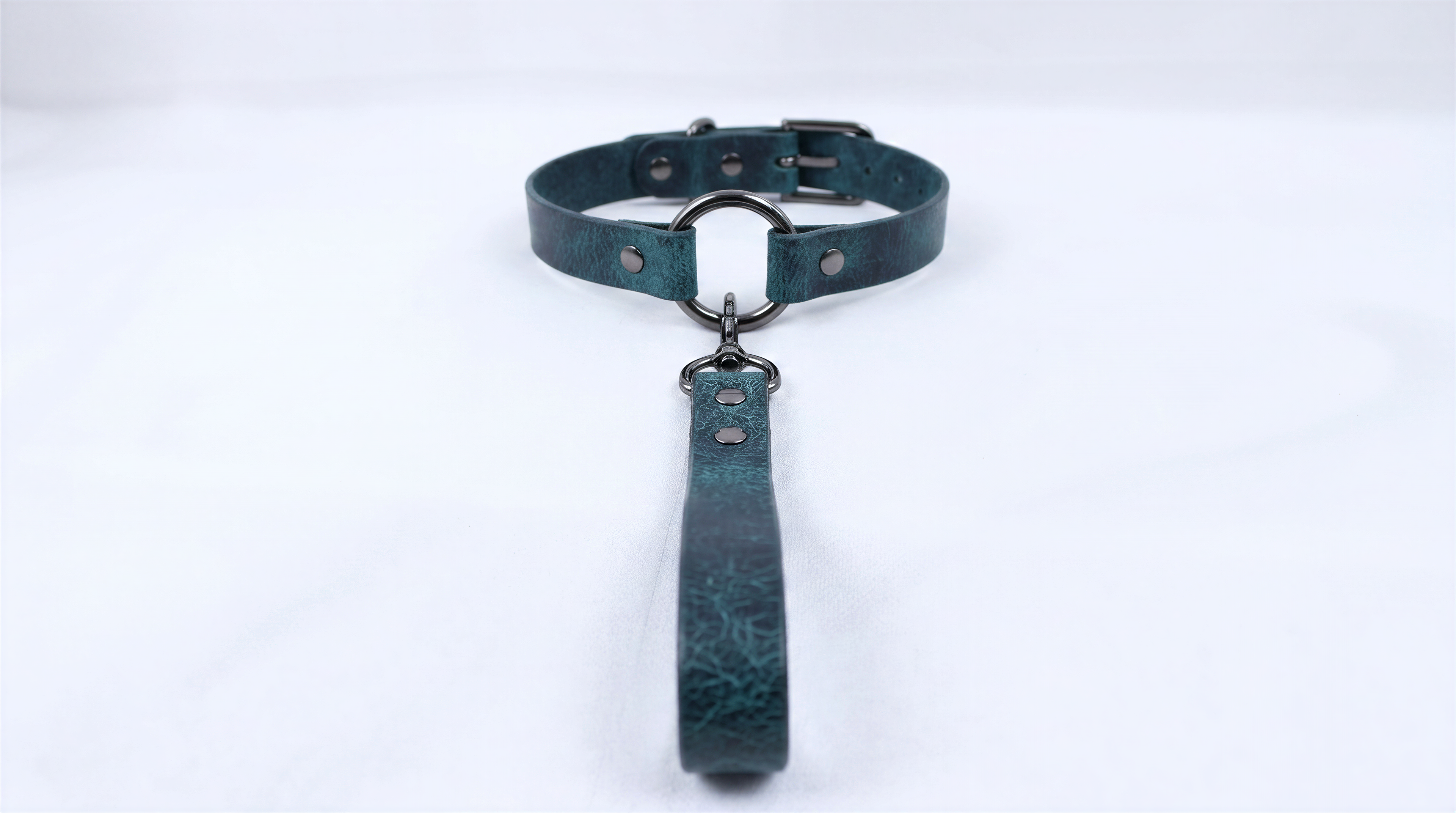 A dark green leather collar with a metal buckle and a handle attached to it.
