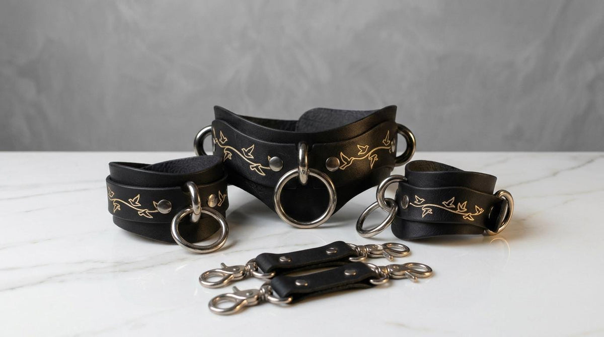 A set of black leather straps with gold floral designs, arranged on a white marble surface.