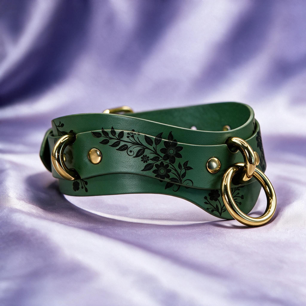 A green leather strap with a floral design and gold-colored metal rings on it, placed on a purple background.