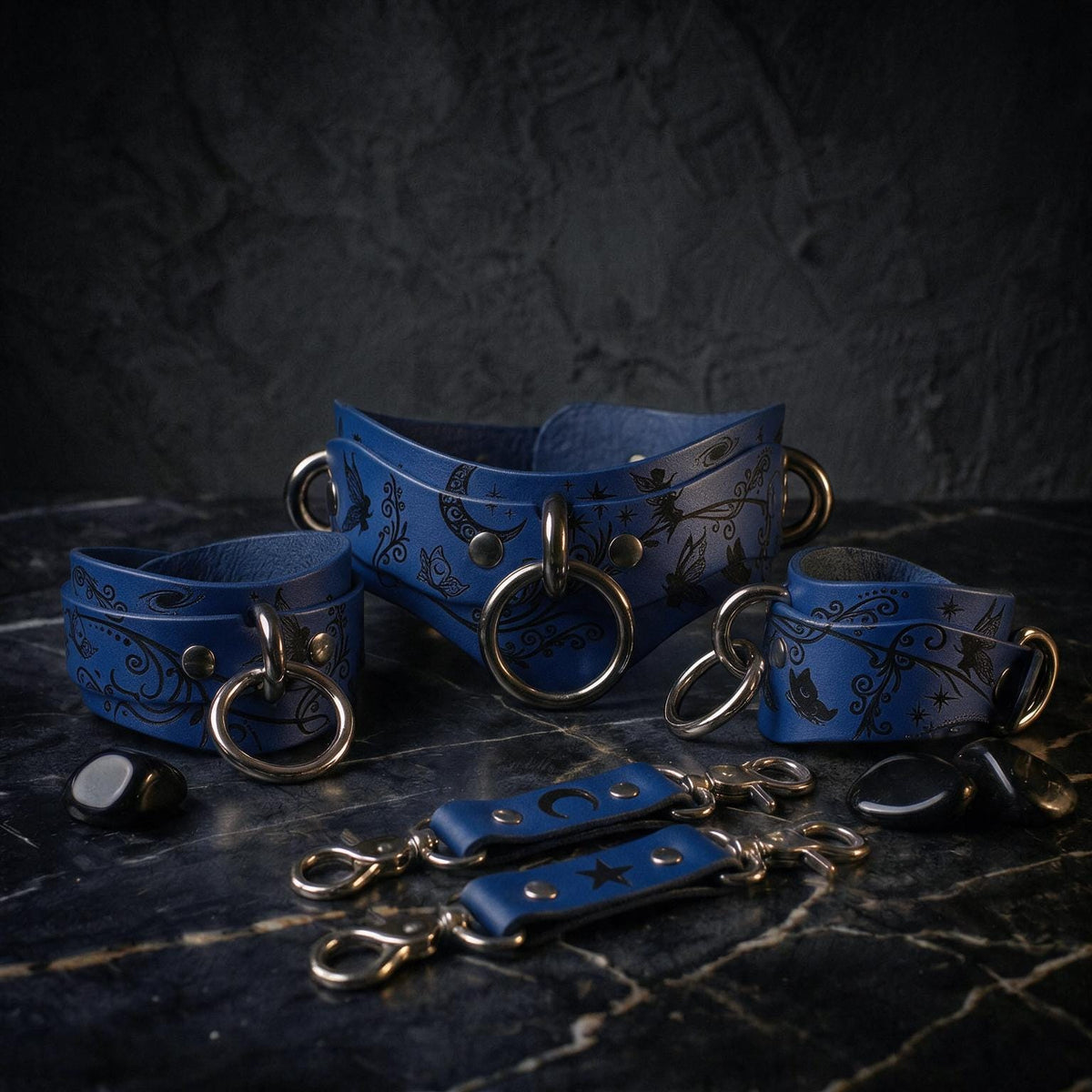A collection of blue leather straps with metal rings and buckles, arranged on a dark surface.