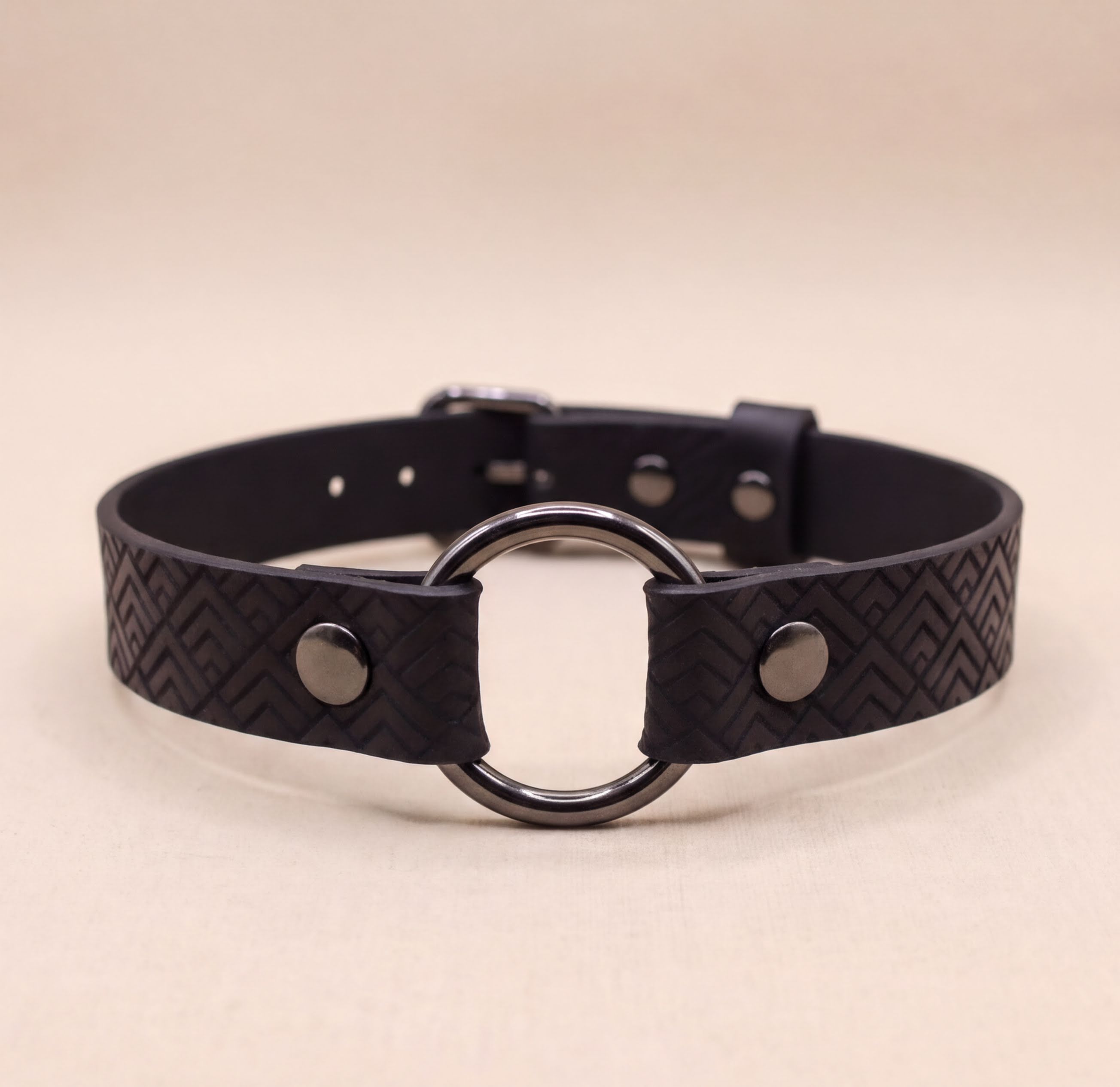 A black leather choker necklace with a metal ring in the center.