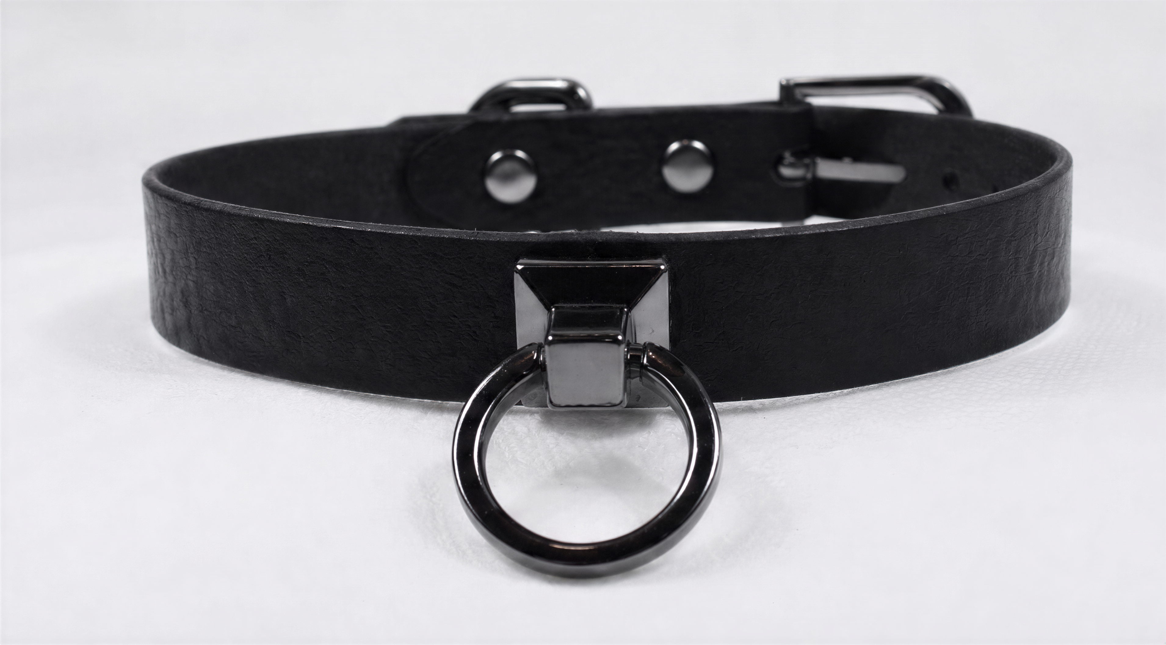 A black leather choker collar with a metal ring and buckle.