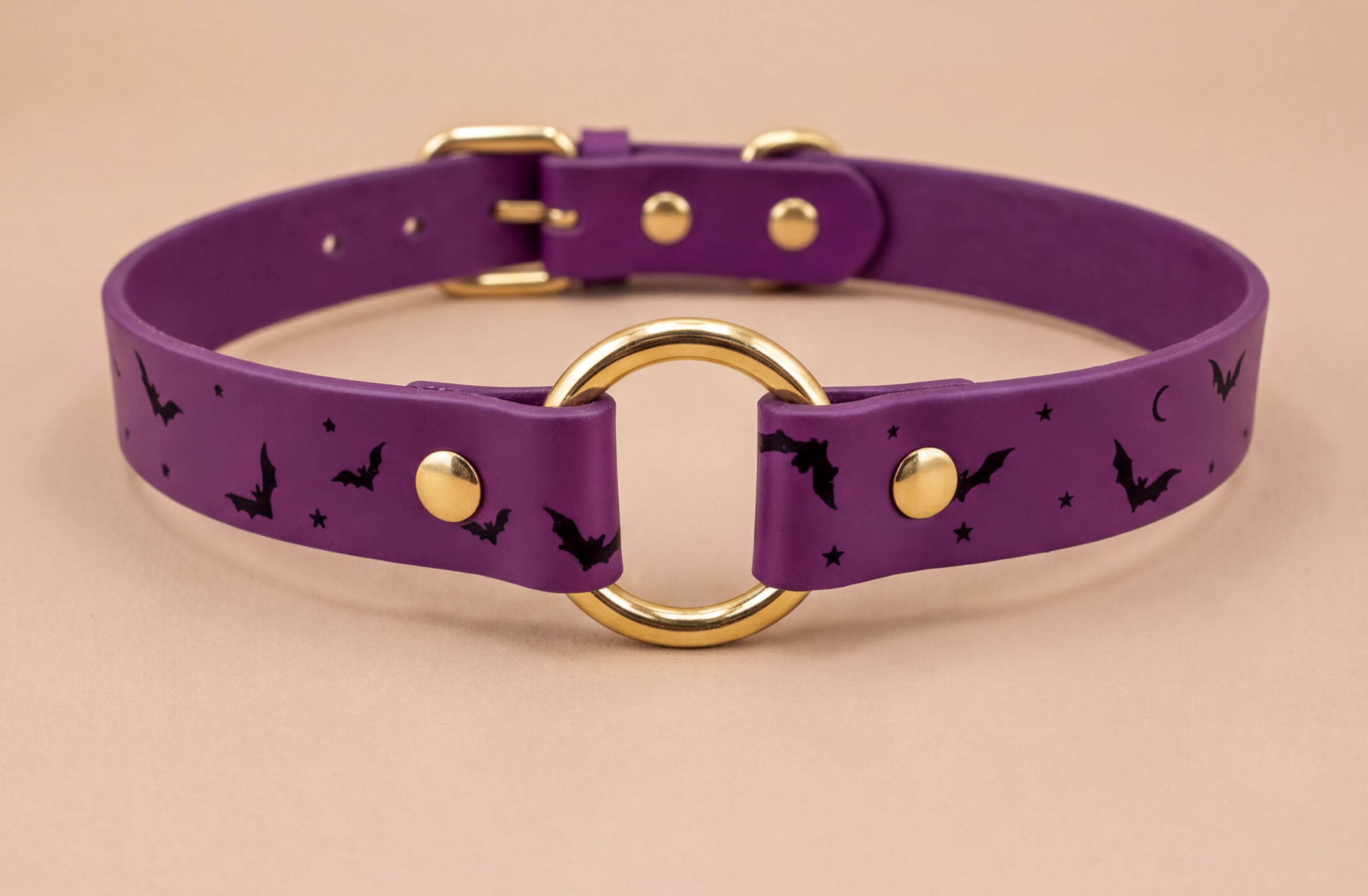 A purple leather collar with a gold ring and bat designs, featuring a purple band with black bats and stars.