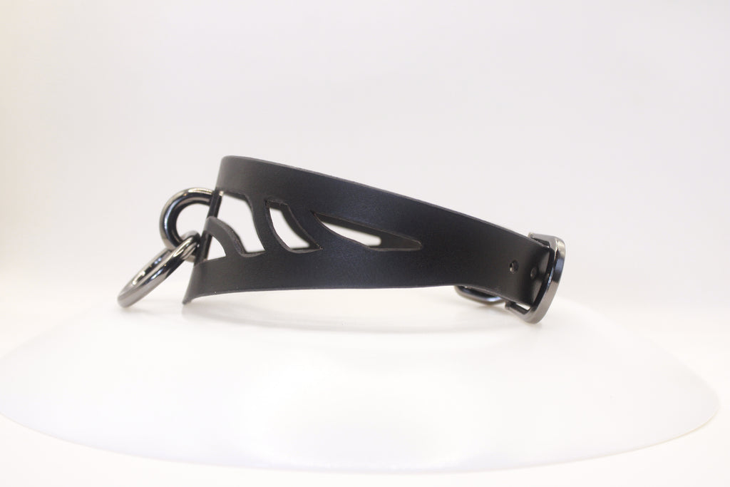 A black leather choker necklace with a cutout design and metal rings.