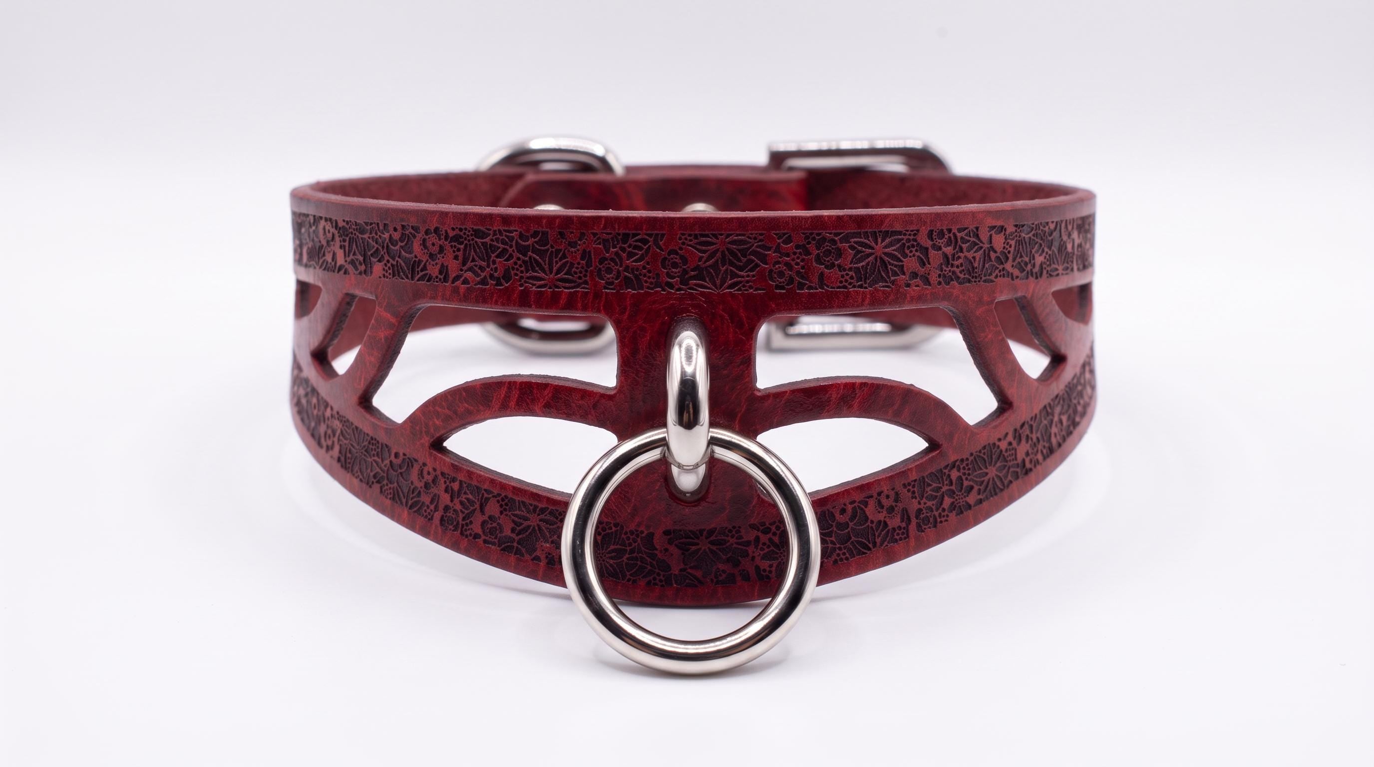 A burgundy leather choker collar with a metal ring and a metal buckle.